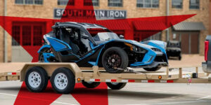 A blue vehicle loaded on a tan PJ car trailer