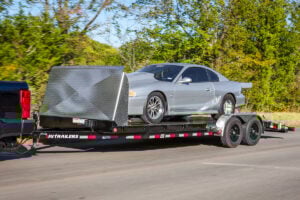 Black PJ Trailers CH car hauler trailer with rock shield, with a silver sports car on top